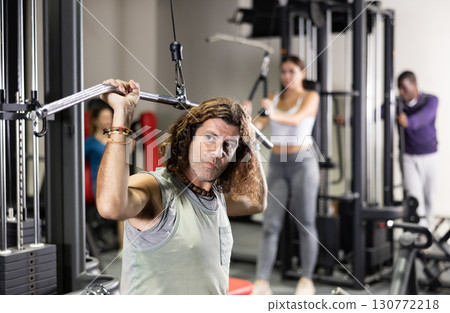 Caucasian man doing exercises on lat pull down machine in gym Caucasian man doing exercises on lat pull down machine in gym 130772218