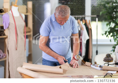 Man cutting paper in sewing workshop 130772336