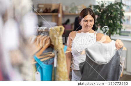 Latin woman customer turn over and choose something summer cloth in store, 130772360
