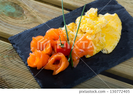 Dish of Norwegian cuisine of cooked omlette fried and served with salmon 130772405
