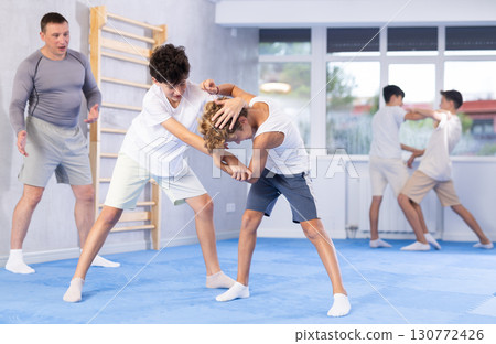 Diligent preteen student practicing self-defense techniques in pairs 130772426