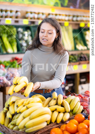 Young woman choosing bananas in vegetable shop Young woman choosing bananas in vegetable shop 130772482