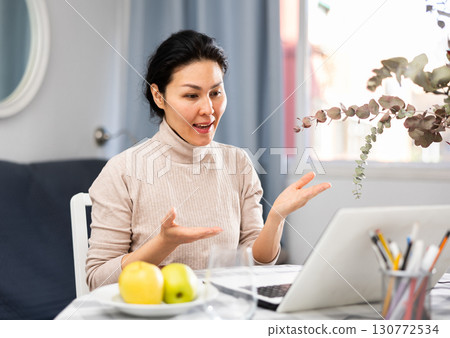 Asian woman communicates with someone via video link 130772534