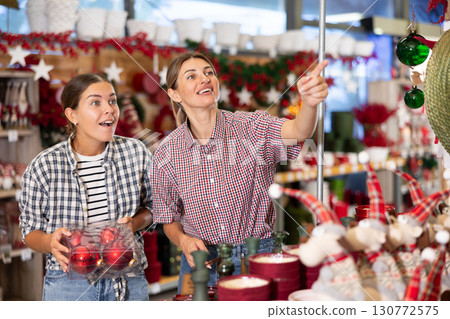 Two cheerful young women choosing Christmas decorations in store Two cheerful young women choosing Christmas decorations in store 130772575