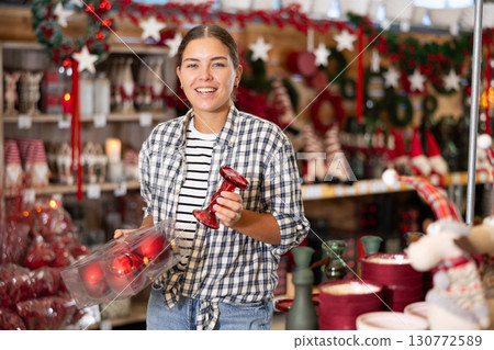 Young woman choosing christmas decorations in store Young woman choosing christmas decorations in store 130772589