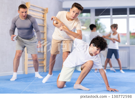 Two boys learn to do painful hand grip in self-defense lesson in sports gym 130772598
