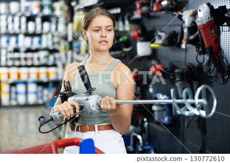 Woman choose examines building mixer in tools department of construction store Woman choose examines building mixer in tools department of construction store 130772610