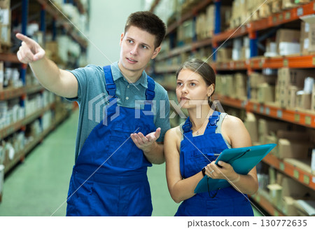 Girl check papers invoices with guy and revise availability of goods in paint and varnish stock 130772635