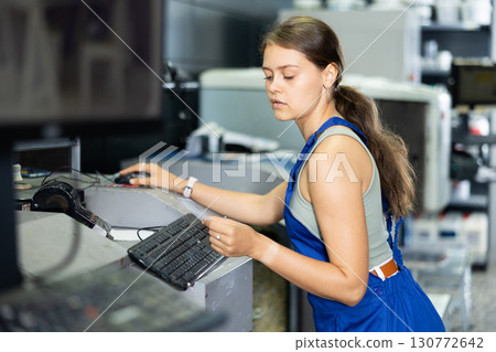 Young woman worker operating computerised machine to mix paint in paint shop 130772642