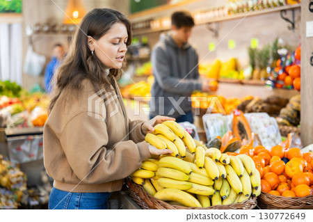 Young woman choosing bananas in vegetable shop 130772649