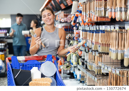 Positive female shopper buying paint brushes at hardware store Positive female shopper buying paint brushes at hardware store 130772674