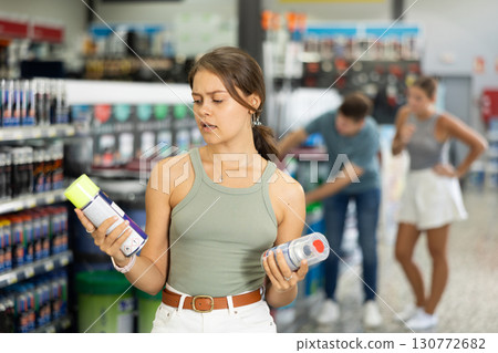 Young female customer buying spray paint can in supermarket 130772682