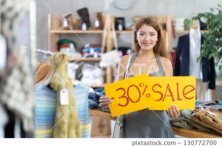 Young woman holding sale sign in clothing store Young woman holding sale sign in clothing store 130772700