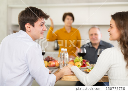 Young couple in love enjoying family dinner with elderly parents Young couple in love enjoying family dinner with elderly parents 130772758