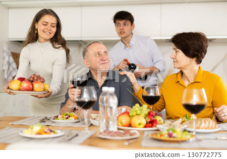 Senior man and woman enjoying family dinner with youth Senior man and woman enjoying family dinner with youth 130772775