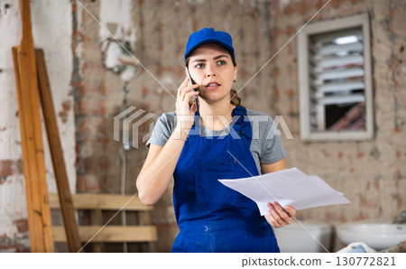 Young woman construction worker talking on phone Young woman construction worker talking on phone 130772821