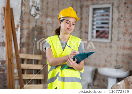 Woman taking notes on indoor construction site 130772829