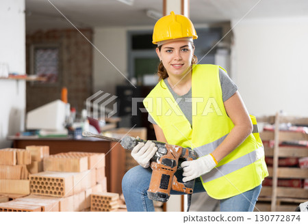 Portrait of positive woman builder standing in construction site Portrait of positive woman builder standing in construction site 130772874