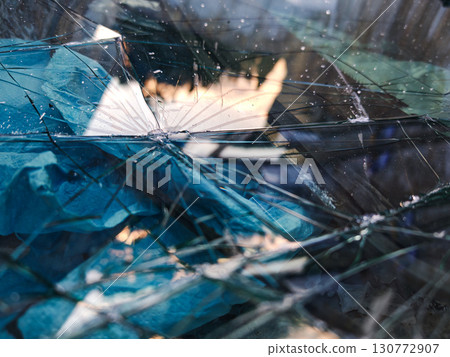 Shattered glass with reflections and blue paper pieces, abstract texture Shattered glass with reflections and blue paper pieces, abstract texture 130772907