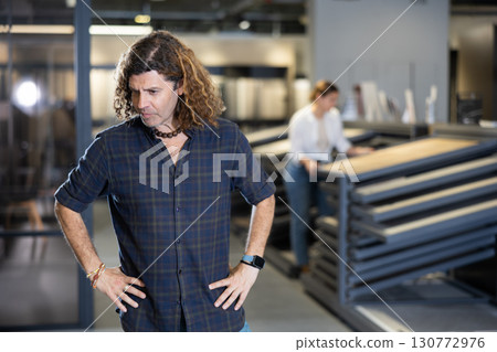 in hardware store, thoughtful man reflects on price-quality ratio of options for parquet flooring in hardware store, thoughtful man reflects on price-quality ratio of options for parquet flooring 130772976