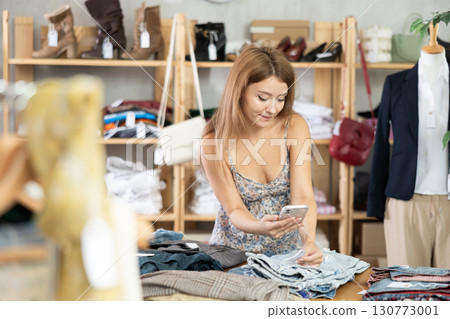 Girl scans QR code and label of denim pantalones using mobile phone camera. Girl scans QR code and label of denim pantalones using mobile phone camera. 130773001