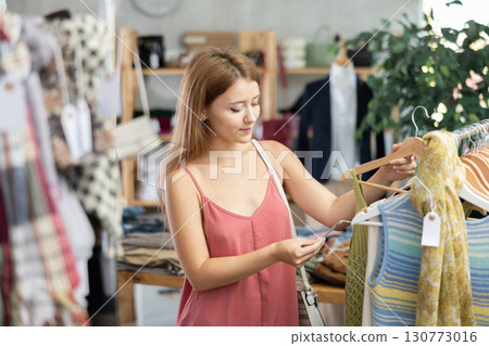 Young woman choosing t-shirt in clothing store Young woman choosing t-shirt in clothing store 130773016