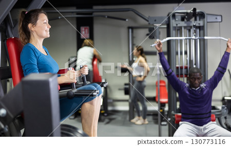 Caucasian woman doing leg raises on captains chair in gym 130773116