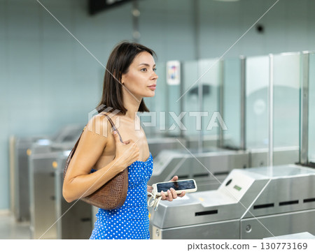 Adult woman passing through turnstile in subway Adult woman passing through turnstile in subway 130773169