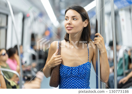 Adult woman stands in subway car Adult woman stands in subway car 130773186
