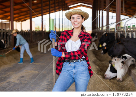 Portrait of a young positive girl in a cowshed 130773234