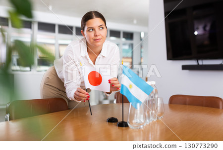 Young lady sets miniatures flags of Argentina and Japan for international negotiations 130773290