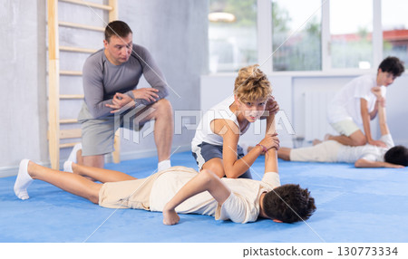 Teens practicing armlock in training bout during self defence course 130773334