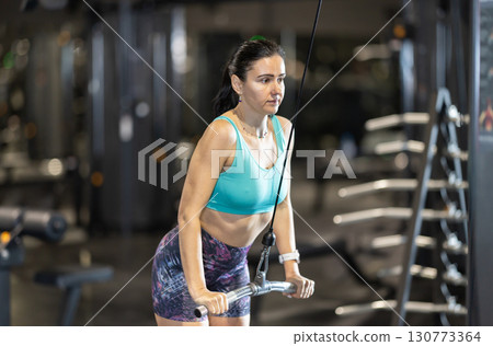Woman working on triceps on cable machine at gym 130773364