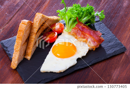 Breakfast from fried egg, bacon and grilled bread 130773405