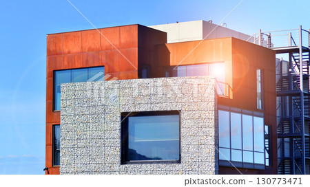 Office building facade covered in unique Corten steel, stones and glass materials. 130773471