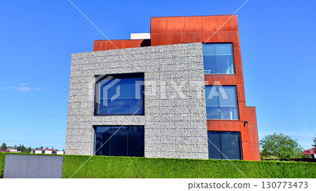 Office building facade covered in unique Corten steel, stones and glass materials. Office building facade covered in unique Corten steel, stones and glass materials. 130773473