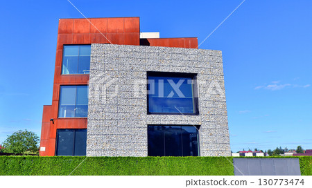 Office building facade covered in unique Corten steel, stones and glass materials. Office building facade covered in unique Corten steel, stones and glass materials. 130773474