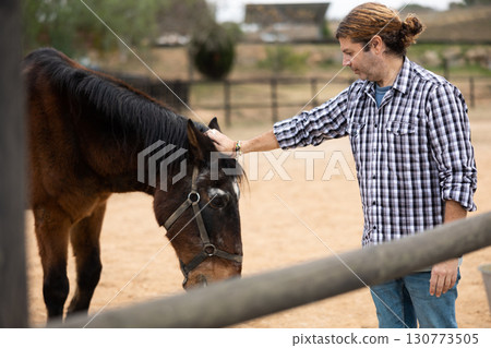 Man taking care of horses on farm 130773505