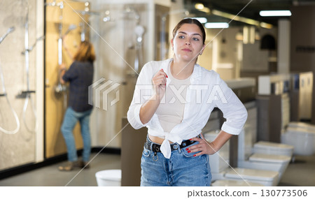 in plumbing department, woman thought about choosing suitable bathroom for new apartment 130773506