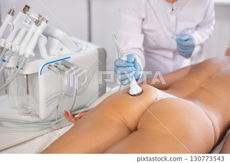 Anti-cellulite hardware massage of buttocks of young woman in beauty clinic Anti-cellulite hardware massage of buttocks of young woman in beauty clinic 130773543