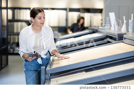 Girl customer choosing ceramic tile at building materials store 130773551