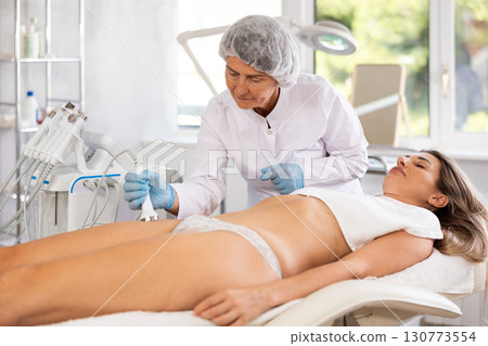 Anti aging thigh hardware therapy procedure for young female client in clinic of aesthetic medicine 130773554