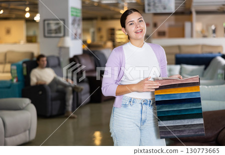 Female furniture salesperson showing different fabric samples in furniture showroom Female furniture salesperson showing different fabric samples in furniture showroom 130773665