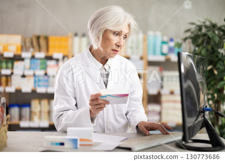 Female pharmacist looking for pills on computer Female pharmacist looking for pills on computer 130773686