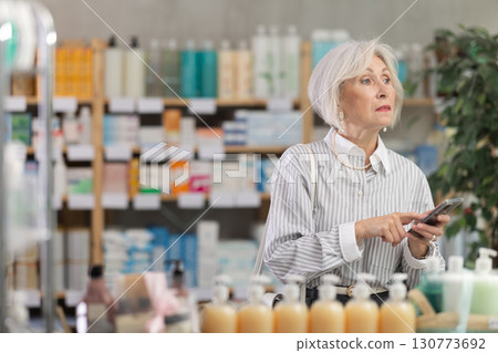 Elderly woman with phone choosing medicines and hygiene products Elderly woman with phone choosing medicines and hygiene products 130773692