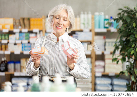 Elderly woman in summer clothes looking for medicine in pharmacy 130773694