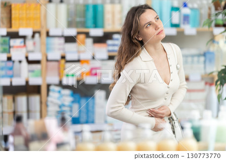 Female shopper experiences abdominal pain while buying in supermarket Female shopper experiences abdominal pain while buying in supermarket 130773770