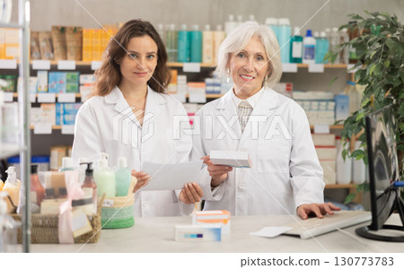 Two female pharmacists inviting a client to a pharmacy Two female pharmacists inviting a client to a pharmacy 130773783