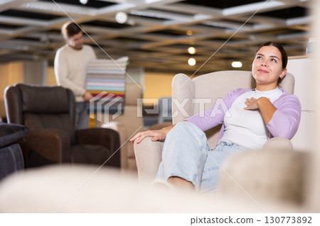 Woman trying out armchair in furniture showroom Woman trying out armchair in furniture showroom 130773892