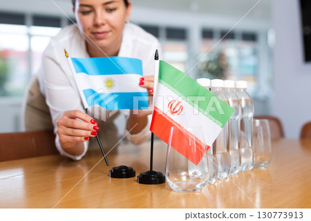 Little flag of Iran on table and flag of Argentina put next to it by young woman Little flag of Iran on table and flag of Argentina put next to it by young woman 130773913
